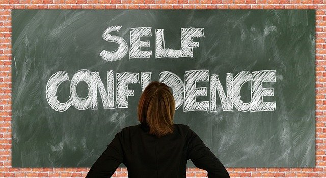 Person looking at chalkboard with 'SELF CONFIDENCE' written on it